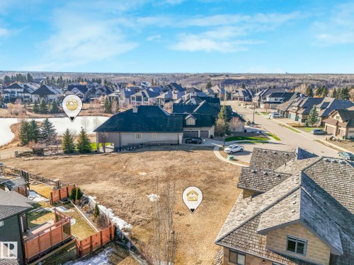 This property offers a spacious yard, with views of a nearby pond and surrounding homes, set within a residential area featuring mature trees and paved roads - 2794 Wheaton Drive, Edmonton, AB 