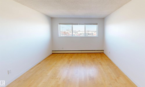 This room features light hardwood flooring, white walls, and a window with a view of the surrounding area - 303 8215 83 Avenue, Edmonton, AB - Indoor Photo Showing Other Room