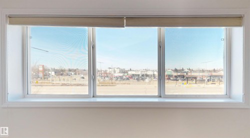 The property features a large window with three panes, offering views of the surrounding area and a clear sky - 303 8215 83 Avenue, Edmonton, AB - Indoor Photo Showing Other Room