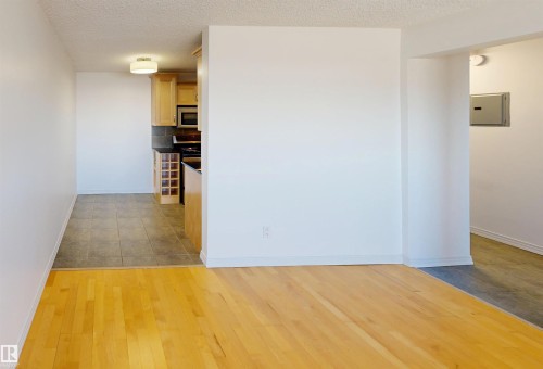 This interior view features light hardwood flooring in the foreground, leading into a tiled area - 303 8215 83 Avenue, Edmonton, AB - Indoor Photo Showing Other Room