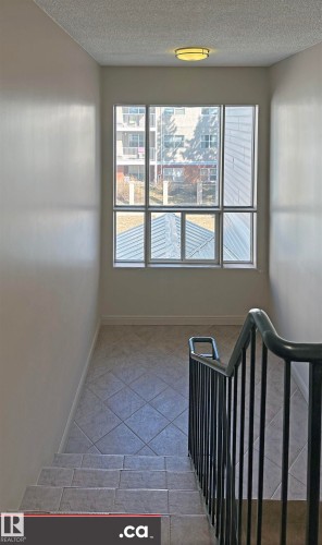 Stairwell featuring tiled floors, a large window, and a dark-colored handrail - 303 8215 83 Avenue, Edmonton, AB - Indoor Photo Showing Other Room