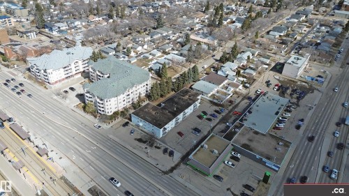 Aerial view showcasing the property's location within a developed neighborhood, featuring commercial buildings with parking areas, and nearby residential structures - 303 8215 83 Avenue, Edmonton, AB -  With View