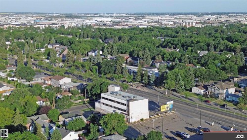 The property features an overhead view of a commercial building with a paved parking lot and a surrounding neighborhood with extensive tree coverage - 303 8215 83 Avenue, Edmonton, AB - Outdoor With View