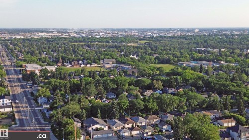 Aerial view of the surrounding neighbourhood, featuring a tree-lined street, residential homes, and distant cityscape - 303 8215 83 Avenue, Edmonton, AB - Outdoor With View