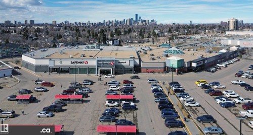 Aerial view showcasing a commercial property with a large parking area and multiple storefronts, including a Safeway grocery store - 303 8215 83 Avenue, Edmonton, AB - Outdoor With View