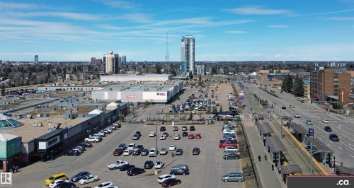 Aerial view highlighting a broad urban landscape with commercial buildings, a parking lot, and a light rail transit line - 303 8215 83 Avenue, Edmonton, AB - Outdoor With View