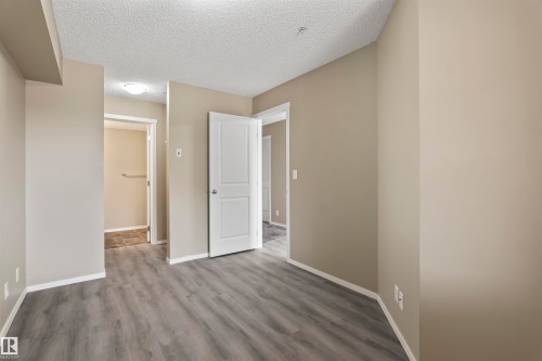 The property features neutral-toned walls, modern grey flooring, and white trim throughout - 214 5816 Mullen Place, Edmonton, AB - Indoor Photo Showing Other Room