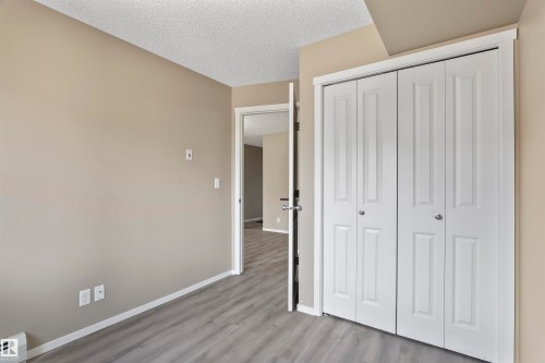 This room features grey flooring, neutral wall paint, and a white bi-fold closet - 214 5816 Mullen Place, Edmonton, AB - Indoor