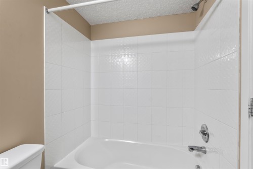 Bathroom featuring a white tiled shower with a coordinating white tub and a chrome showerhead and faucet - 214 5816 Mullen Place, Edmonton, AB - Indoor Photo Showing Bathroom