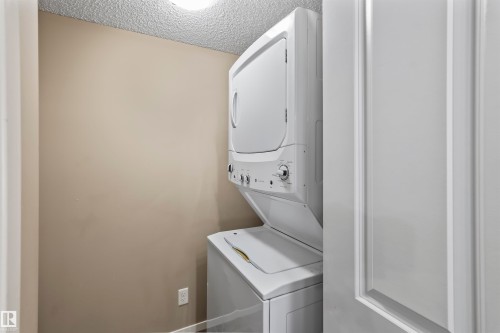 Dedicated laundry area featuring a white stacked washer and dryer unit - 214 5816 Mullen Place, Edmonton, AB - Indoor Photo Showing Laundry Room