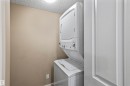 Dedicated laundry area featuring a white stacked washer and dryer unit - 214 5816 Mullen Place, Edmonton, AB  - Indoor Photo Showing Laundry Room 