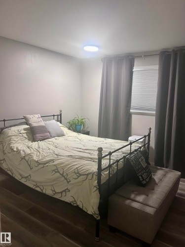 This room features durable plank flooring, a window with blinds, and a ceiling light fixture - 4515 54 Ave, Tofield, AB - Indoor Photo Showing Bedroom
