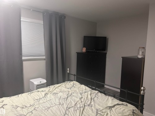 This room features a window with blinds and dark-colored curtains, providing light control - 4515 54 Ave, Tofield, AB - Indoor Photo Showing Bedroom
