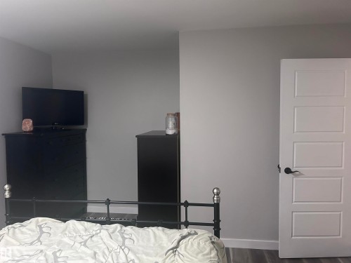 This room features light grey walls and a contemporary five-panel interior door with a black handle - 4515 54 Ave, Tofield, AB - Indoor Photo Showing Bedroom