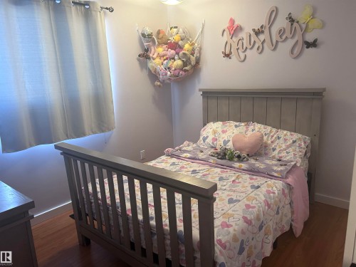 This room features hardwood flooring, a window with curtains, and light-colored walls - 4515 54 Ave, Tofield, AB - Indoor Photo Showing Bedroom
