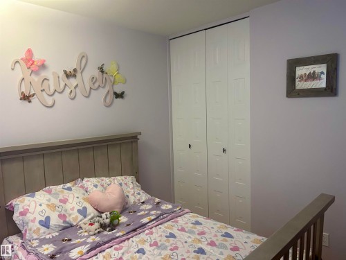 This room features a neutral-toned headboard and a built-in closet with paneled bifold doors - 4515 54 Ave, Tofield, AB - Indoor Photo Showing Bedroom