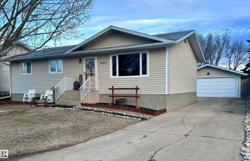 The property features a concrete driveway leading to a detached garage with a white sectional door - 4515 54 Ave, Tofield, AB - Outdoor