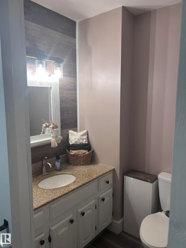 Bathroom featuring a granite countertop vanity with white cabinetry, a mirror with an overhead light fixture, and a toilet - 4515 54 Ave, Tofield, AB - Indoor Photo Showing Bathroom