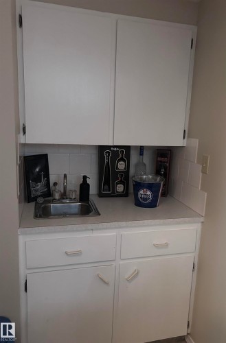 Functional utility space featuring a compact sink, white cabinetry with silver hardware, and a light-colored countertop - 4515 54 Ave, Tofield, AB - Indoor Photo Showing Kitchen