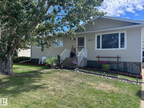 The property features a well-maintained exterior with siding, a front lawn, and mature trees - 4515 54 Ave, Tofield, AB - Outdoor