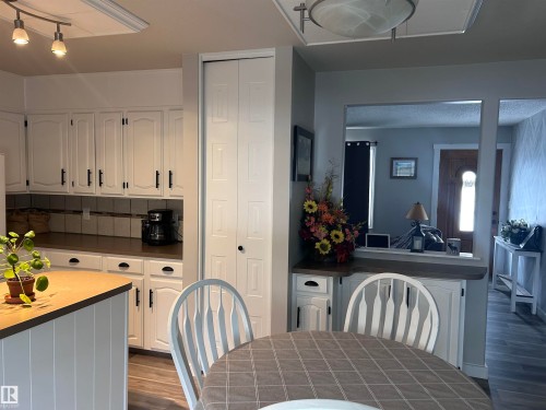 The kitchen features white cabinetry with black hardware, a tiled backsplash, and recessed lighting - 4515 54 Ave, Tofield, AB - Indoor Photo Showing Dining Room