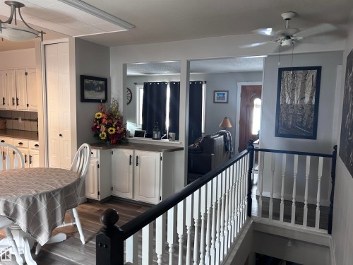 This interior view highlights a dining area with a round table, white chairs, and wood-look flooring - 4515 54 Ave, Tofield, AB - Indoor Photo Showing Other Room