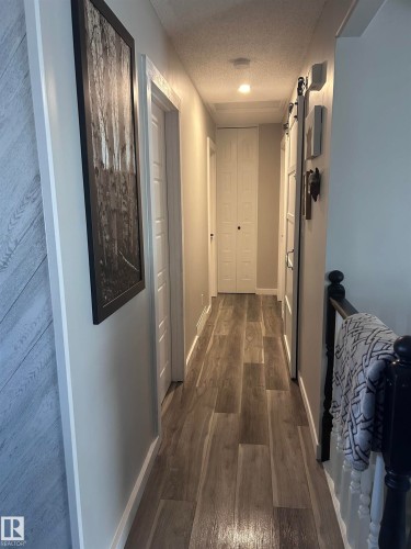 This property features a well-lit hallway with light wood-style flooring and white doors - 4515 54 Ave, Tofield, AB - Indoor Photo Showing Other Room