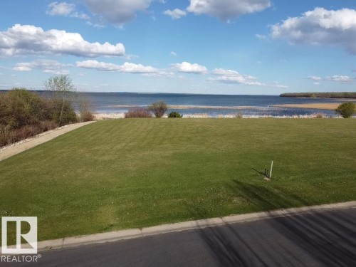 Expansive green lawn with a clear view of the water and distant shoreline - #1 Sunset Harbour, Rural Wetaskiwin County, AB 
