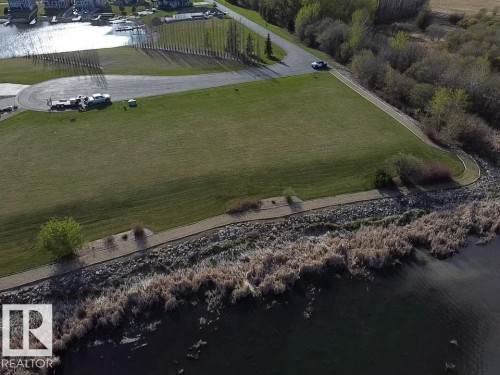 Expansive grassy lot with waterfront views, featuring a paved road and a walking path - #1 Sunset Harbour, Rural Wetaskiwin County, AB 