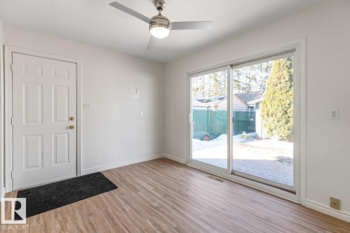 This room features light-colored walls, wood-style flooring, a ceiling fan, and sliding glass doors that open to the exterior - 13108 133 Street, Edmonton, AB - Indoor Photo Showing Other Room
