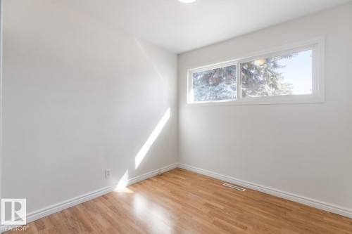This room features hardwood floors and a window with views of snow-covered trees - 13108 133 Street, Edmonton, AB - Indoor Photo Showing Other Room