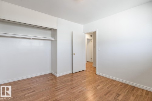 The room features wood-style flooring and a closet with hanging rods and an upper shelf - 13108 133 Street, Edmonton, AB - Indoor Photo Showing Other Room