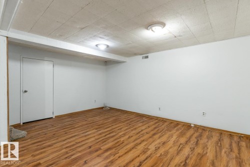 Spacious room with wood-style flooring and white walls, featuring overhead lighting and a white door - 13108 133 Street, Edmonton, AB - Indoor Photo Showing Other Room