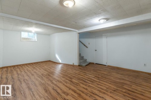 Spacious room featuring wood-look flooring, light-colored walls, and a window - 13108 133 Street, Edmonton, AB - Indoor