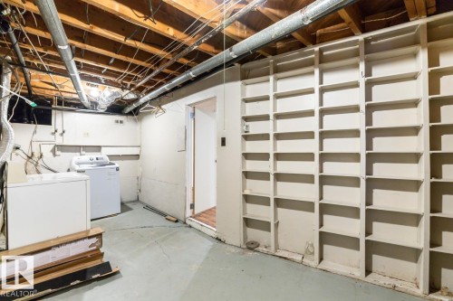 The property features a utility area with concrete flooring, exposed ceiling joists, and a spacious built-in shelving unit - 13108 133 Street, Edmonton, AB - Indoor Photo Showing Laundry Room