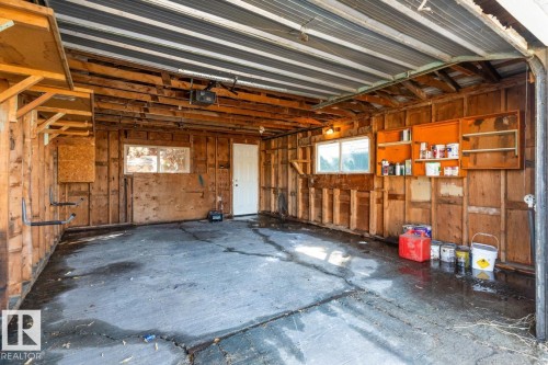 The property includes a spacious garage with exposed wood framing, a concrete floor, and a corrugated metal ceiling - 13108 133 Street, Edmonton, AB - Indoor