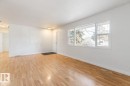 Bright living space with light-toned wood flooring and a large window providing views of exterior trees - 13108 133 Street, Edmonton, AB  - Indoor Photo Showing Other Room 