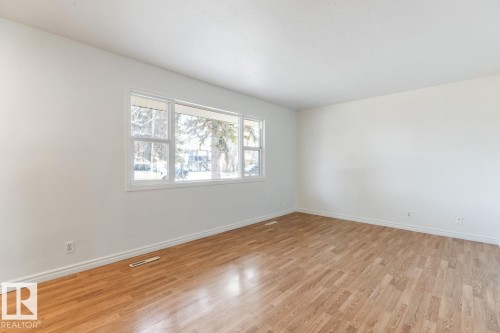 Spacious room with light-colored flooring and white walls, featuring a large window that provides natural light - 13108 133 Street, Edmonton, AB - Indoor Photo Showing Other Room