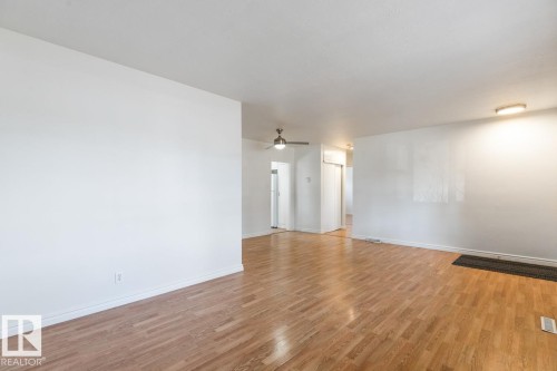 This spacious room features hardwood flooring, white walls, and a ceiling fan - 13108 133 Street, Edmonton, AB - Indoor Photo Showing Other Room