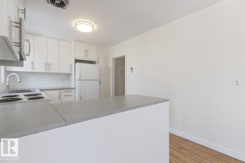 The kitchen features white cabinetry, a white tile backsplash, and a contemporary light fixture - 13108 133 Street, Edmonton, AB - Indoor Photo Showing Kitchen
