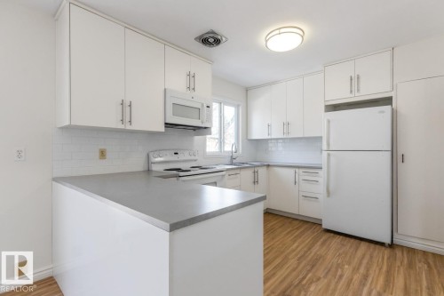 The kitchen features white cabinetry, a white subway tile backsplash, and a white refrigerator - 13108 133 Street, Edmonton, AB - Indoor Photo Showing Kitchen