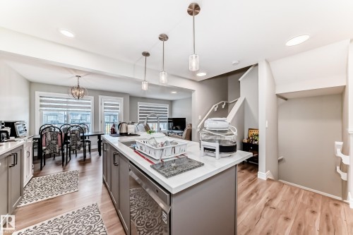 The property features an open-concept living area with hardwood flooring, a kitchen island with pendant lighting, and recessed lighting throughout - 7822 Koruluk Link Link, Edmonton, AB - Indoor Photo Showing Kitchen With Upgraded Kitchen