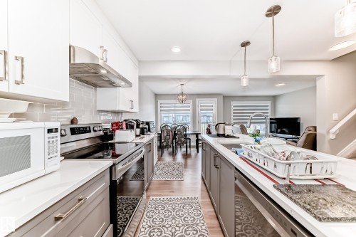 The kitchen features white upper cabinetry, grey lower cabinetry, stainless steel appliances, and light-colored countertops - 7822 Koruluk Link Link, Edmonton, AB - Indoor Photo Showing Kitchen With Upgraded Kitchen