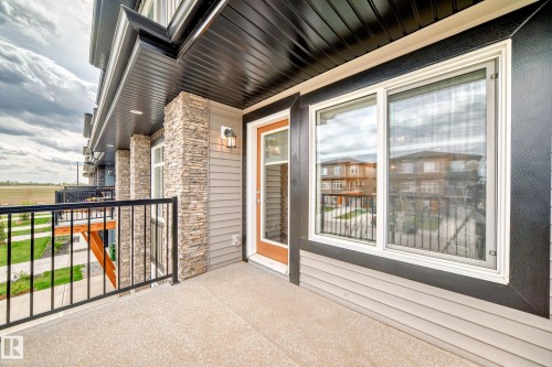 This property features a balcony with a black metal railing and a stone pillar accent - 7822 Koruluk Link Link, Edmonton, AB - Outdoor With Balcony With Exterior