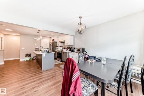 The open concept layout features engineered wood flooring throughout, with a kitchen island providing additional counter space and seating - 7822 Koruluk Link Link, Edmonton, AB - Indoor Photo Showing Dining Room
