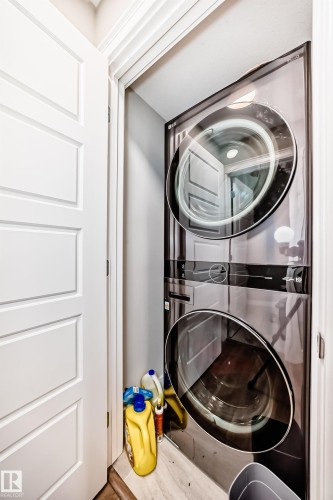 Laundry area featuring a stacked washer and dryer, with a white door and light flooring - 7822 Koruluk Link Link, Edmonton, AB - Indoor Photo Showing Laundry Room