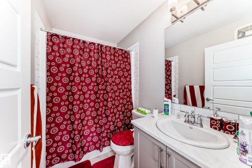 The bathroom features a vanity with a white countertop and an oval sink, complemented by a large mirror and overhead lighting - 7822 Koruluk Link Link, Edmonton, AB - Indoor Photo Showing Bathroom
