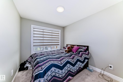 This room features light-colored walls and carpeting, a window with horizontal blinds, and a ceiling light fixture - 7822 Koruluk Link Link, Edmonton, AB - Indoor Photo Showing Bedroom