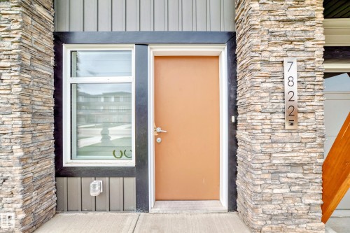 The property features stone cladding accents, a modern front door, and a prominent house number display - 7822 Koruluk Link Link, Edmonton, AB - Outdoor