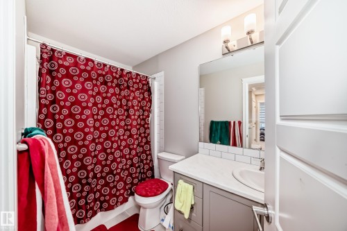 This bathroom features a vanity with a white countertop and an undermount sink, a subway tile backsplash, and a large mirror with overhead lighting - 7822 Koruluk Link Link, Edmonton, AB - Indoor Photo Showing Bathroom